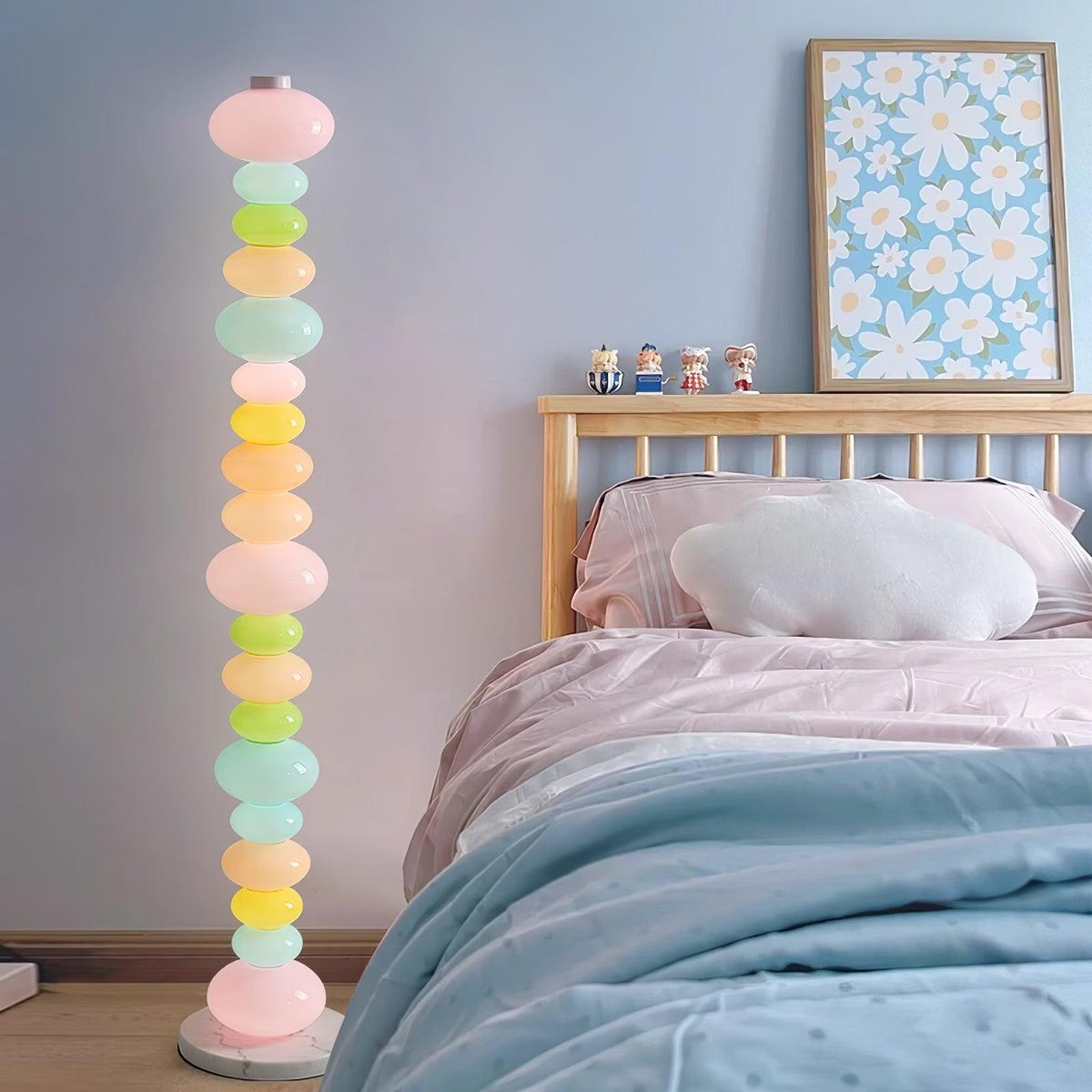 Beside a wooden bed frame and floral wall art, this Clérachic floor lamp's globe column lights a pale blue bedroom.
