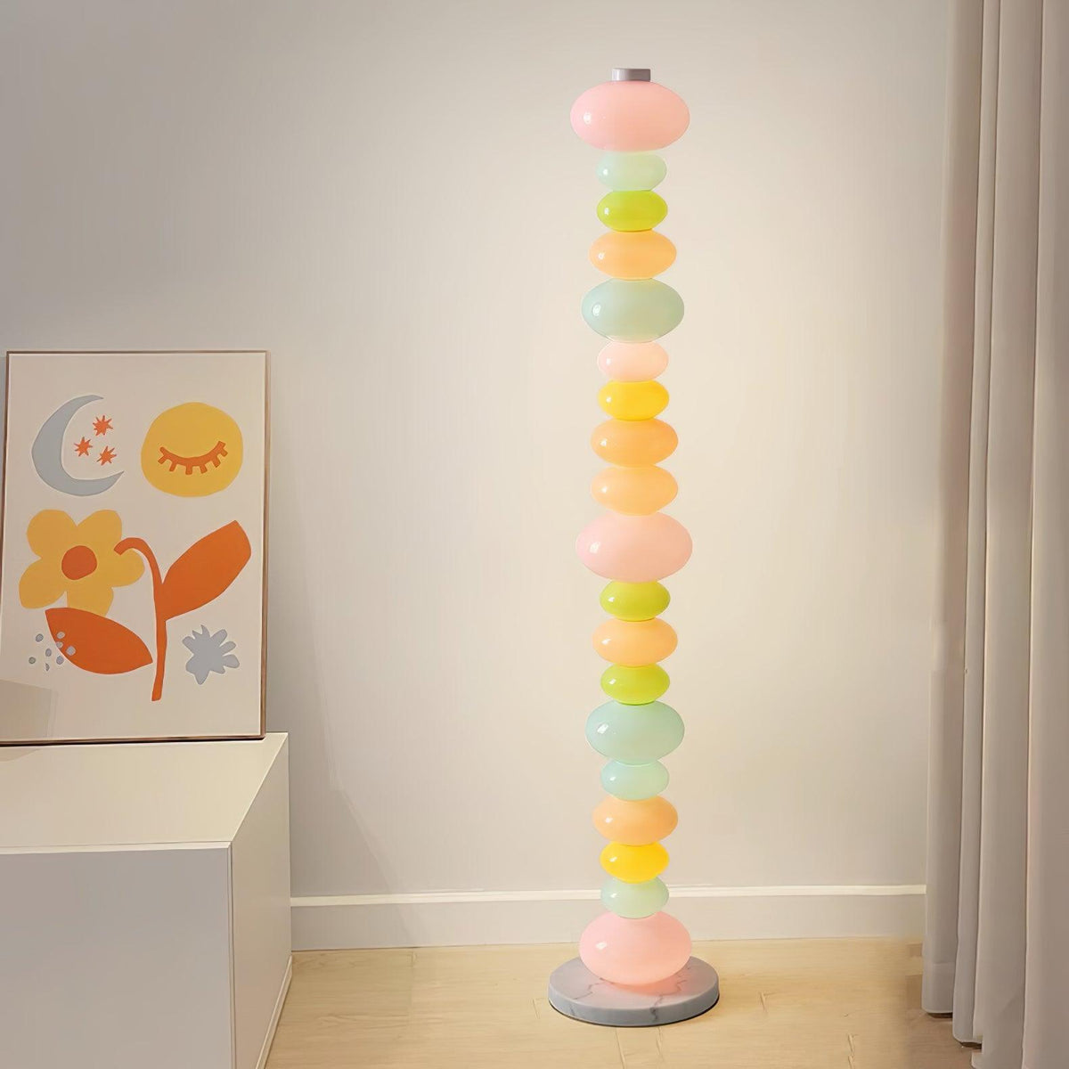 In a room corner beneath a moon and flower print, this Clérachic floor lamp's stacked globes stand beside a white cabinet.