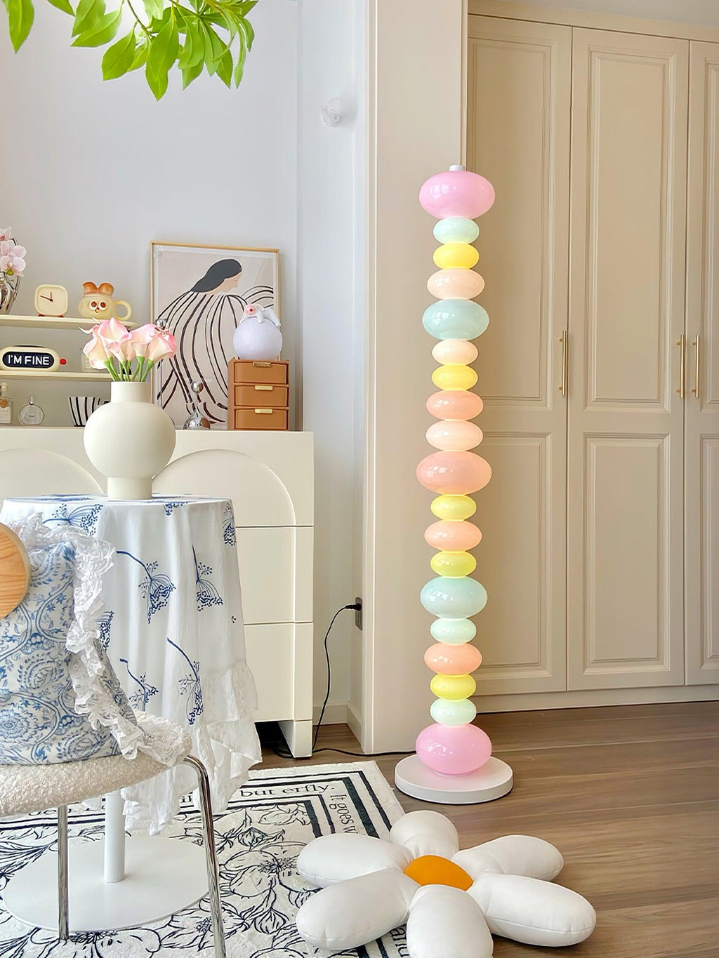 On a floral tablecloth table with a vase of flowers, this Clérachic floor lamp's globes glow near soft plush cushions.