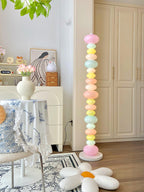On a floral tablecloth table with a vase of flowers, this Clérachic floor lamp's globes glow near soft plush cushions.