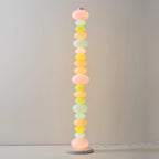Set against a plain pale wall, this Clérachic floor lamp shows its stacked pastel glass globes in a minimal setting.