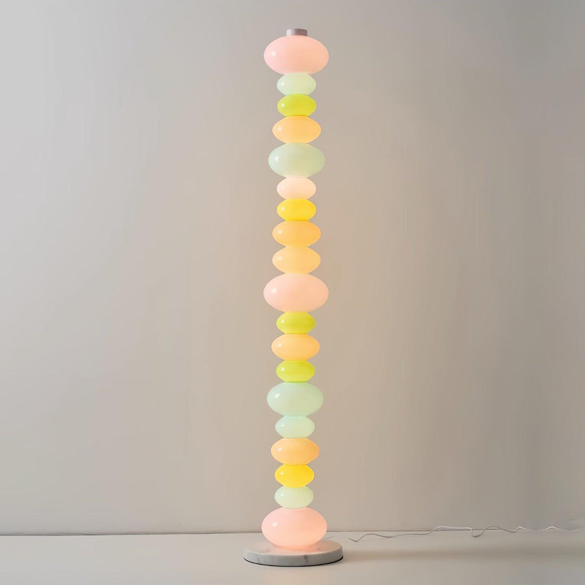 Set against a plain pale wall, this Clérachic floor lamp shows its stacked pastel glass globes in a minimal setting.