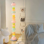 Near a ladder shelf of photographs and a bear figure, this Clérachic floor lamp's globes glow beside a soft cream throw.