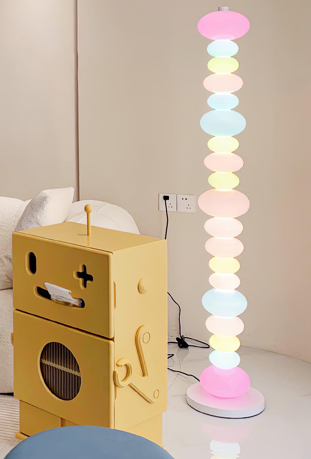 Next to a yellow robot-shaped toy and a blue ottoman, this Clérachic floor lamp's stacked globes glow in a bright room.