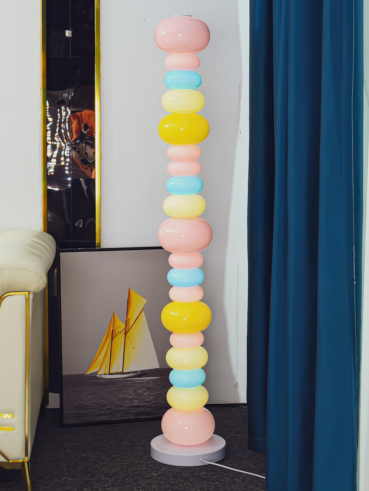 Beside a cream armchair and a blue curtain, this Clérachic floor lamp's globe column glows near framed sailboat art.
