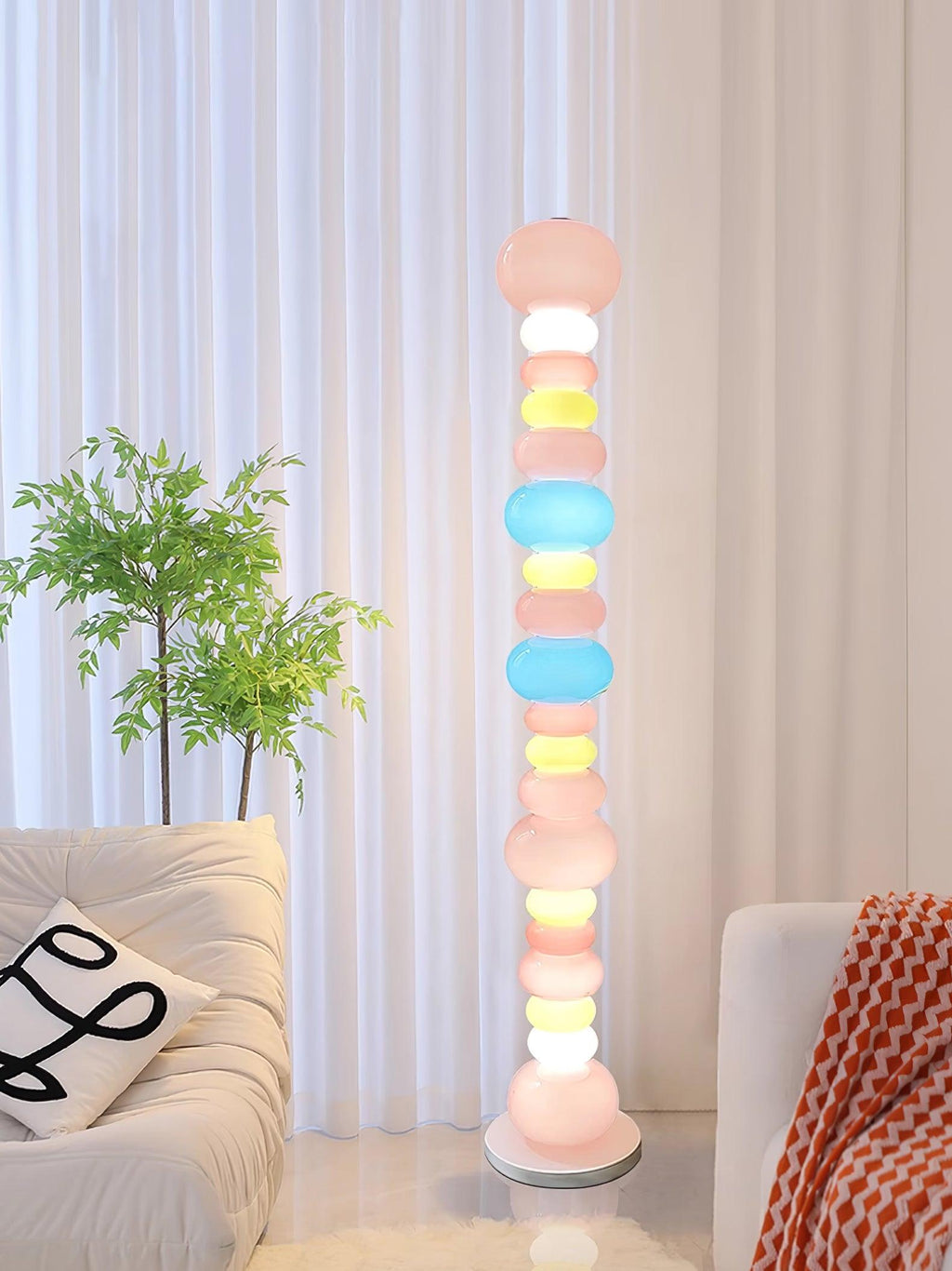 Beside a cream sofa with a red patterned throw and a potted plant, this Clérachic floor lamp's globes glow softly.