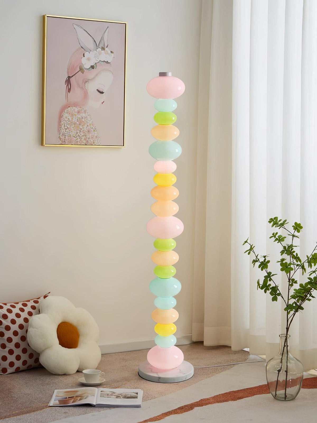 Under a pink portrait print and near a floral cushion, this Clérachic floor lamp's globe column glows beside a plant.