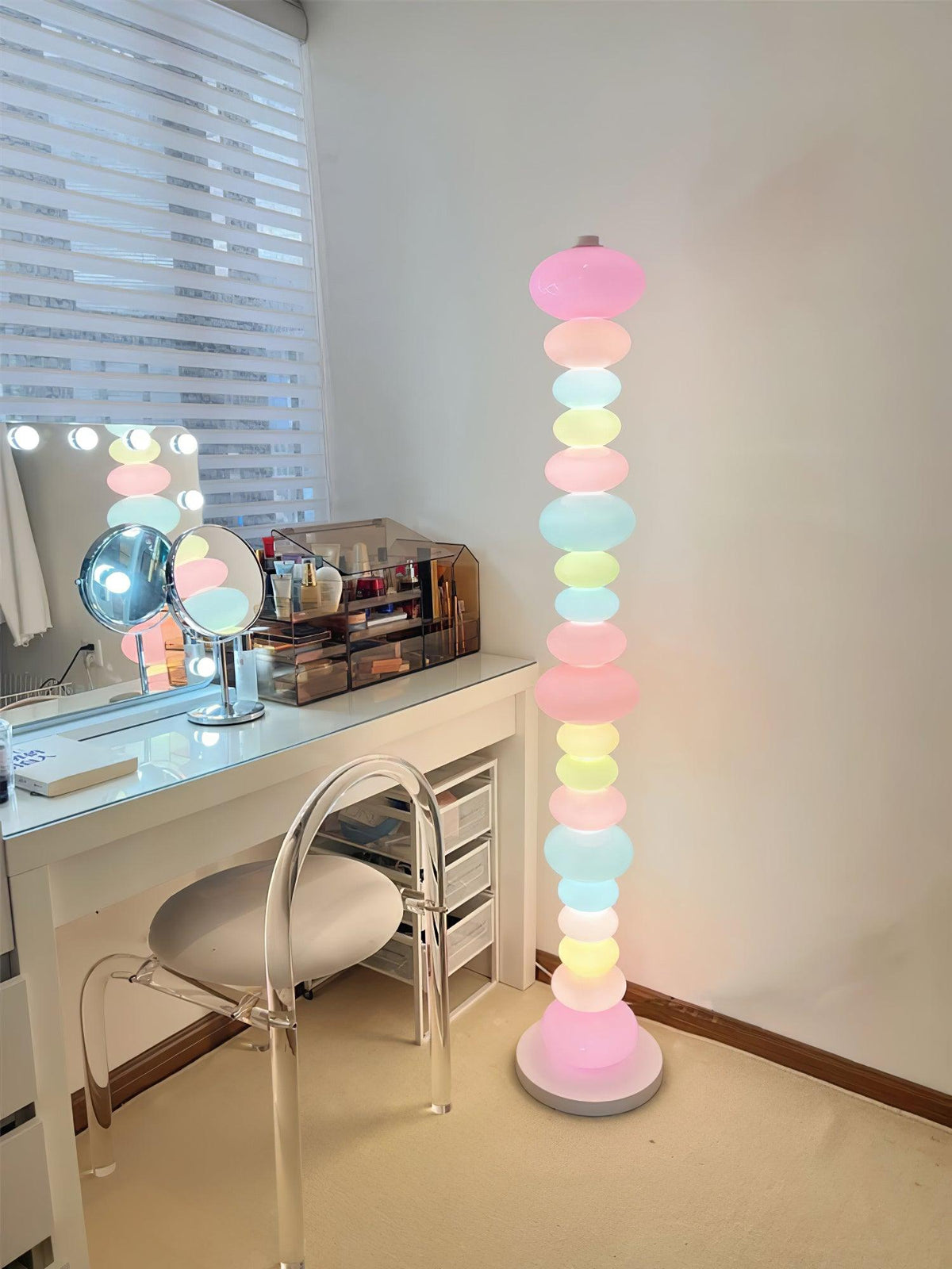 Beside a lit vanity mirror and dressing table, this Clérachic floor lamp's globe column glows on a tan carpet.