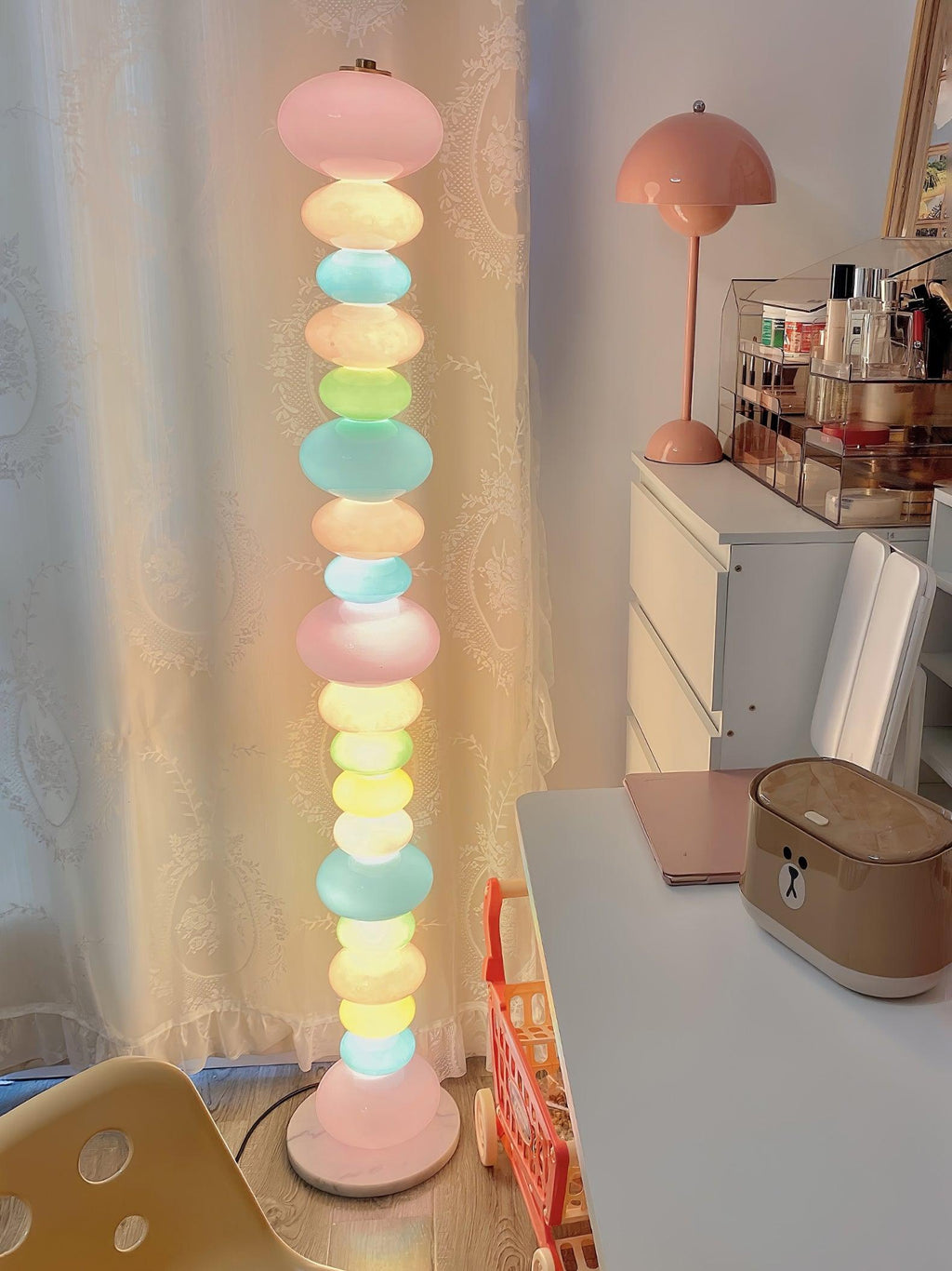 Near a dressing table with cosmetics and a sheer curtain, this Clérachic floor lamp's globe column glows softly.