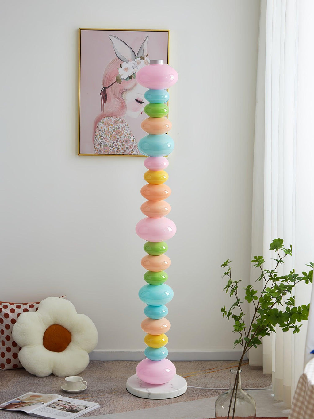 Under a framed portrait print and beside a floral cushion, this Clérachic floor lamp's globe column glows near a plant.