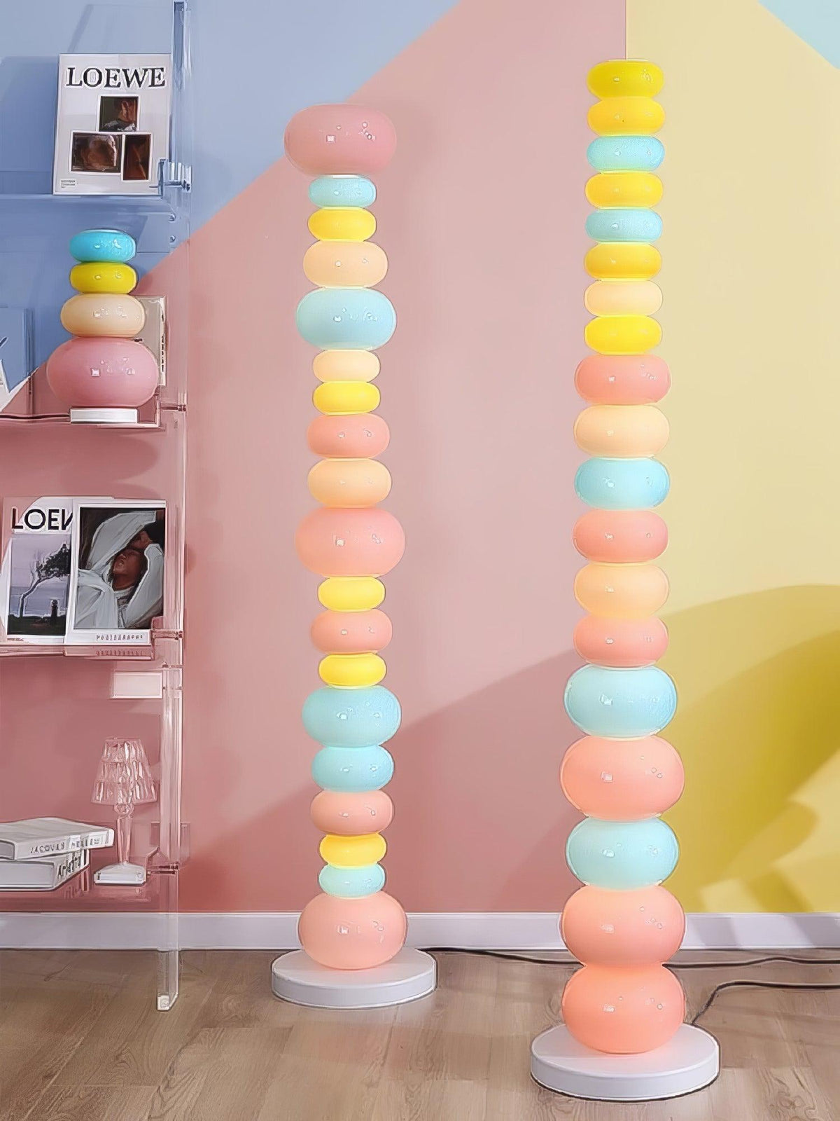 Three Clérachic floor lamps stand together against a pink and yellow wall, each column of glass globes lit in soft colour.