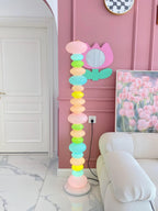 Beside a flower-shaped mirror and pink panelled wall, this Clérachic floor lamp's globe column glows near a cream sofa.