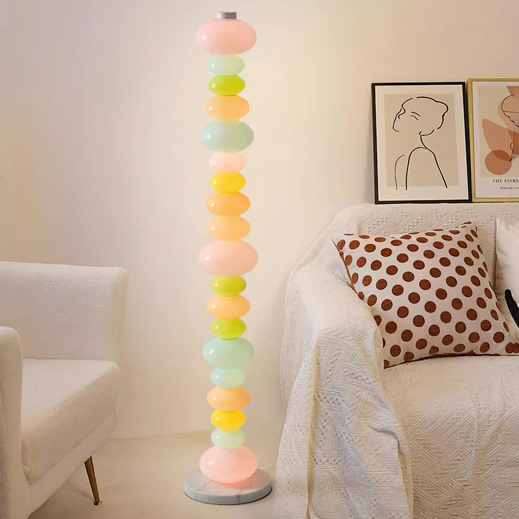 Clérachic multicolour floor lamp lit beside a cream armchair with a polka-dot cushion and framed portrait prints.