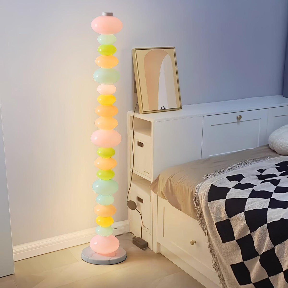 Clérachic glass globe floor lamp lit beside a white dresser with an oval mirror, next to a bed with a chequered throw.