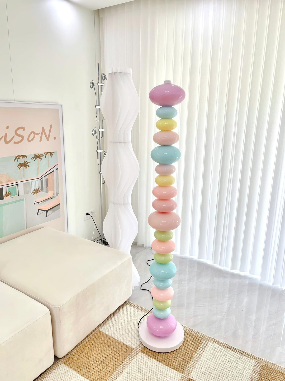 Beside a woven wall lamp and a plaid rug, this Clérachic floor lamp's globe column glows in a cream-toned living room.