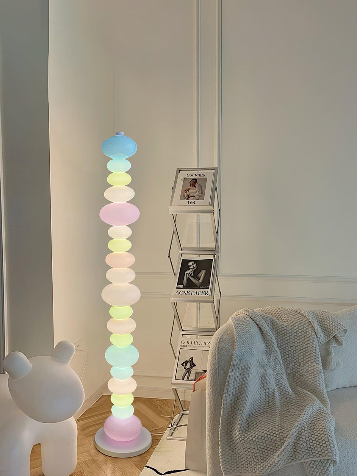 Beside the same bear figure and photo shelf, this Clérachic floor lamp shows a blue globe glowing at its crown.