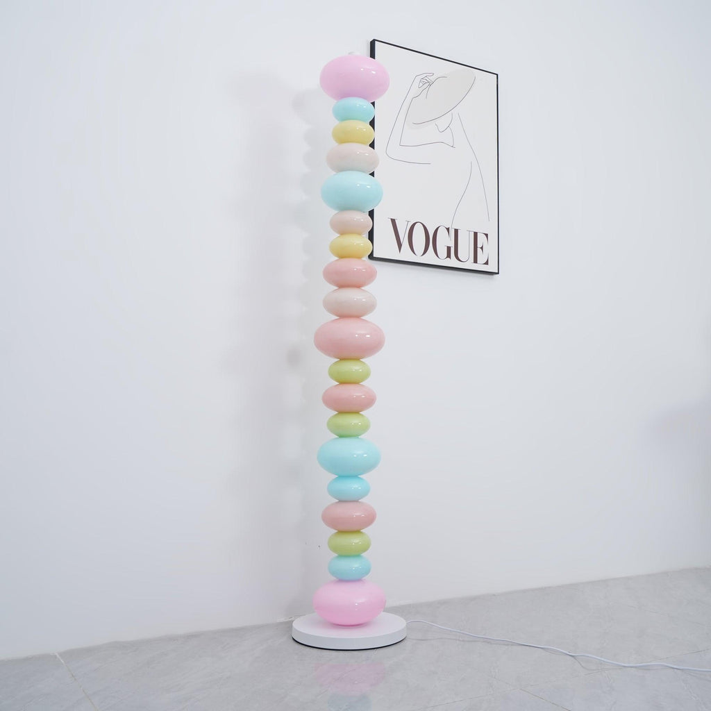 Clérachic glass globe floor lamp shown unlit in daylight beside a 'VOGUE' wall print, its pastel colours flat and matte.