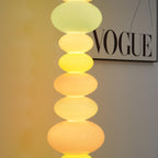 Close crop of a Clérachic glass globe lamp's top orbs glowing warm yellow, with a 'VOGUE' print visible behind.