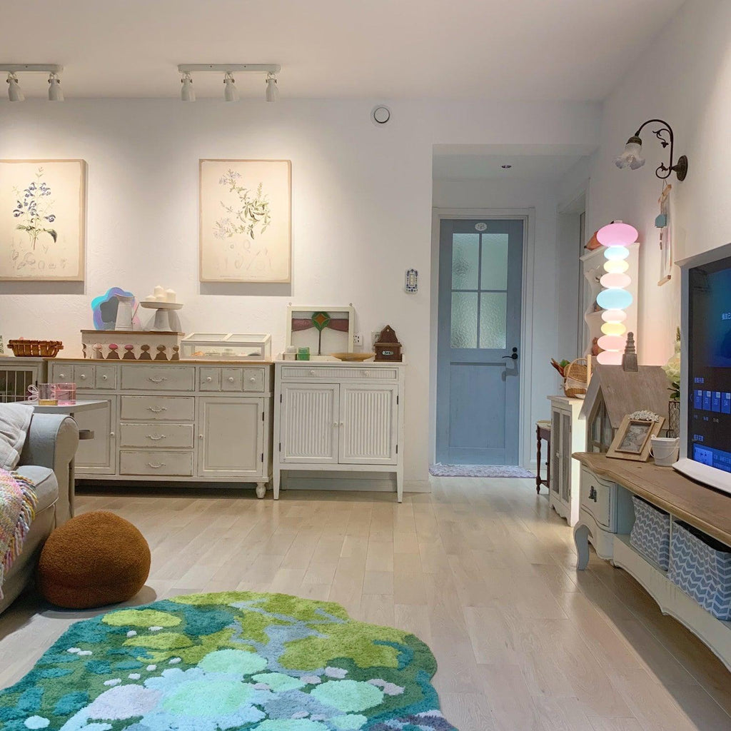 Clérachic glass globe floor lamp lit in a hallway with framed botanical prints and a pale blue panelled door.