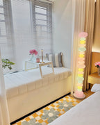 Clérachic stacked glass globe lamp glowing in a window seat corner with striped cushions and sheer curtains.