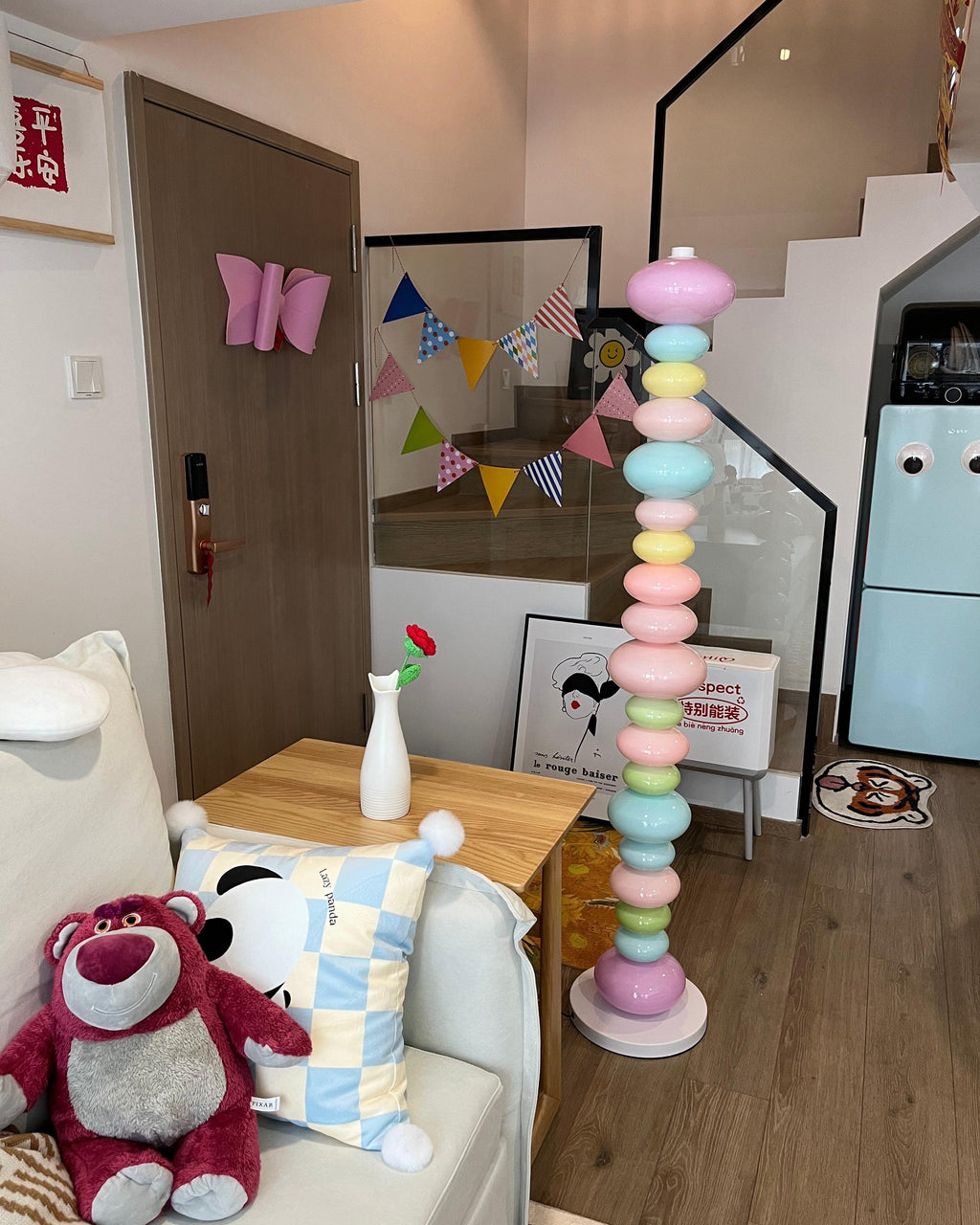 Clérachic multicolour floor lamp lit on a stair landing, beside a teddy bear toy and hanging paper bunting.