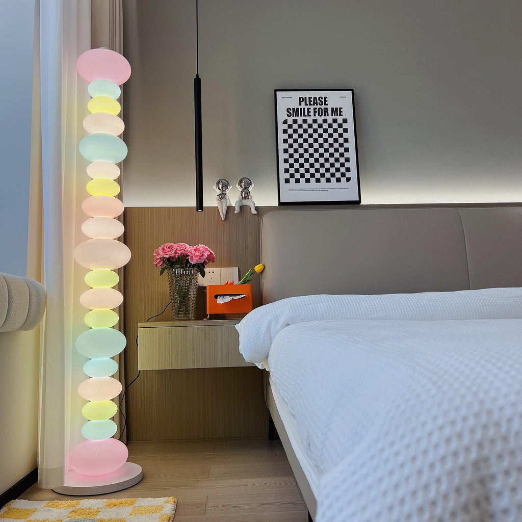 Close crop of a Clérachic pastel floor lamp glowing beside a 'please smile for me' print and a vase of flowers.