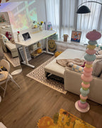 Clérachic multicolour floor lamp lit in a home office corner, beside a white desk and a geometric patterned rug.