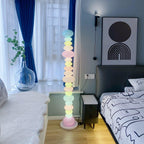 Clérachic pastel floor lamp glowing in a bedroom with doodle-print bedding and a navy curtain accent.