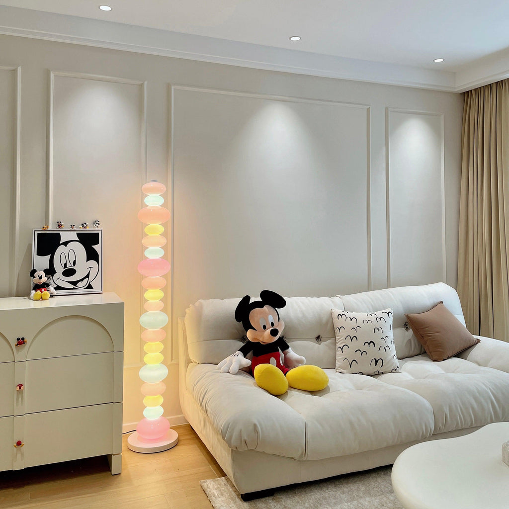 Clérachic glass globe floor lamp glowing beside a cream sofa, with Mickey Mouse plush toys propped against it.