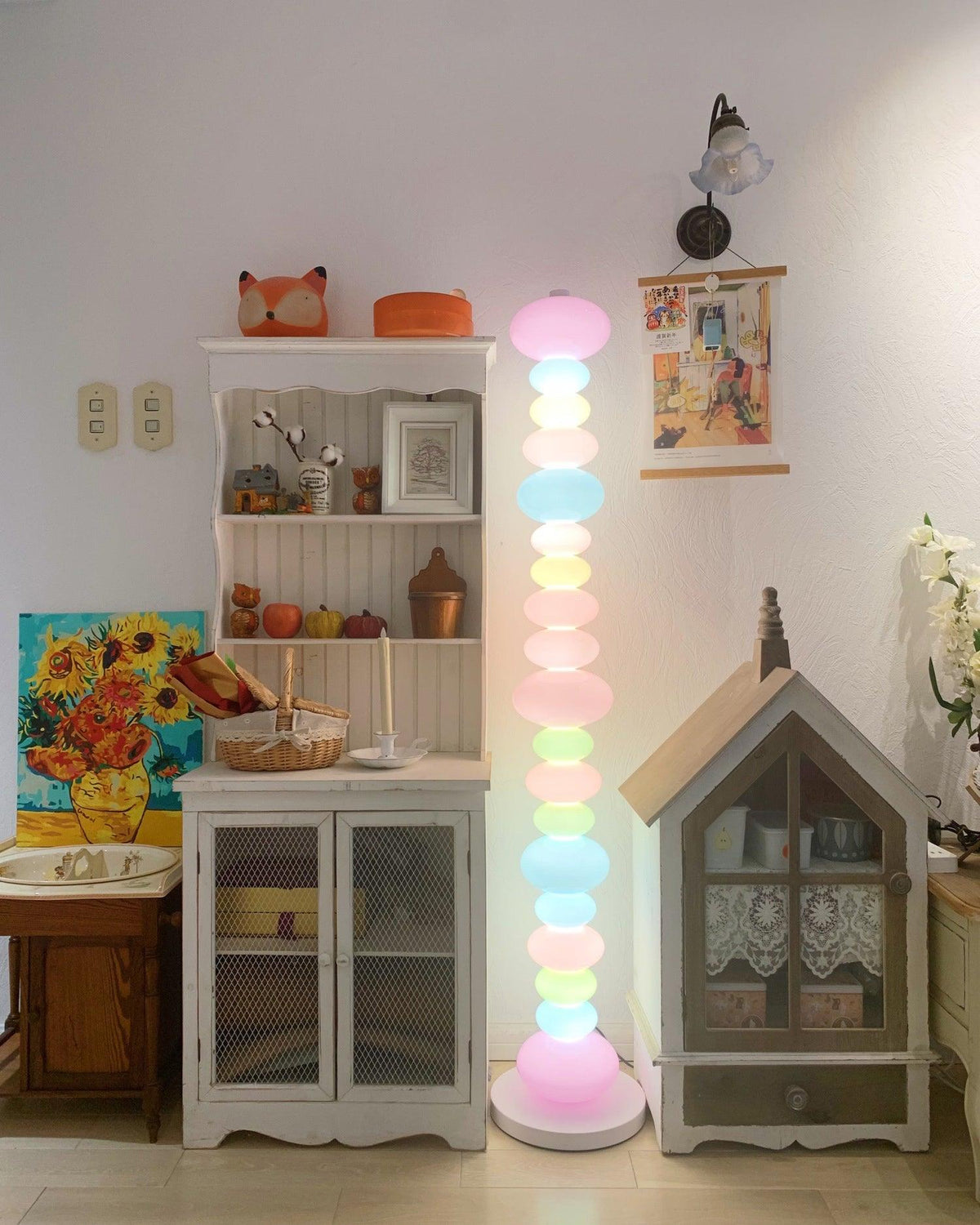 Clérachic pastel floor lamp glowing beside a bookshelf and dollhouse, with a sunflower painting on the wall.