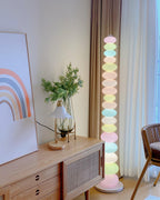 Clérachic stacked glass globe floor lamp lit beside a wooden cabinet, a small table lamp and a rainbow print.