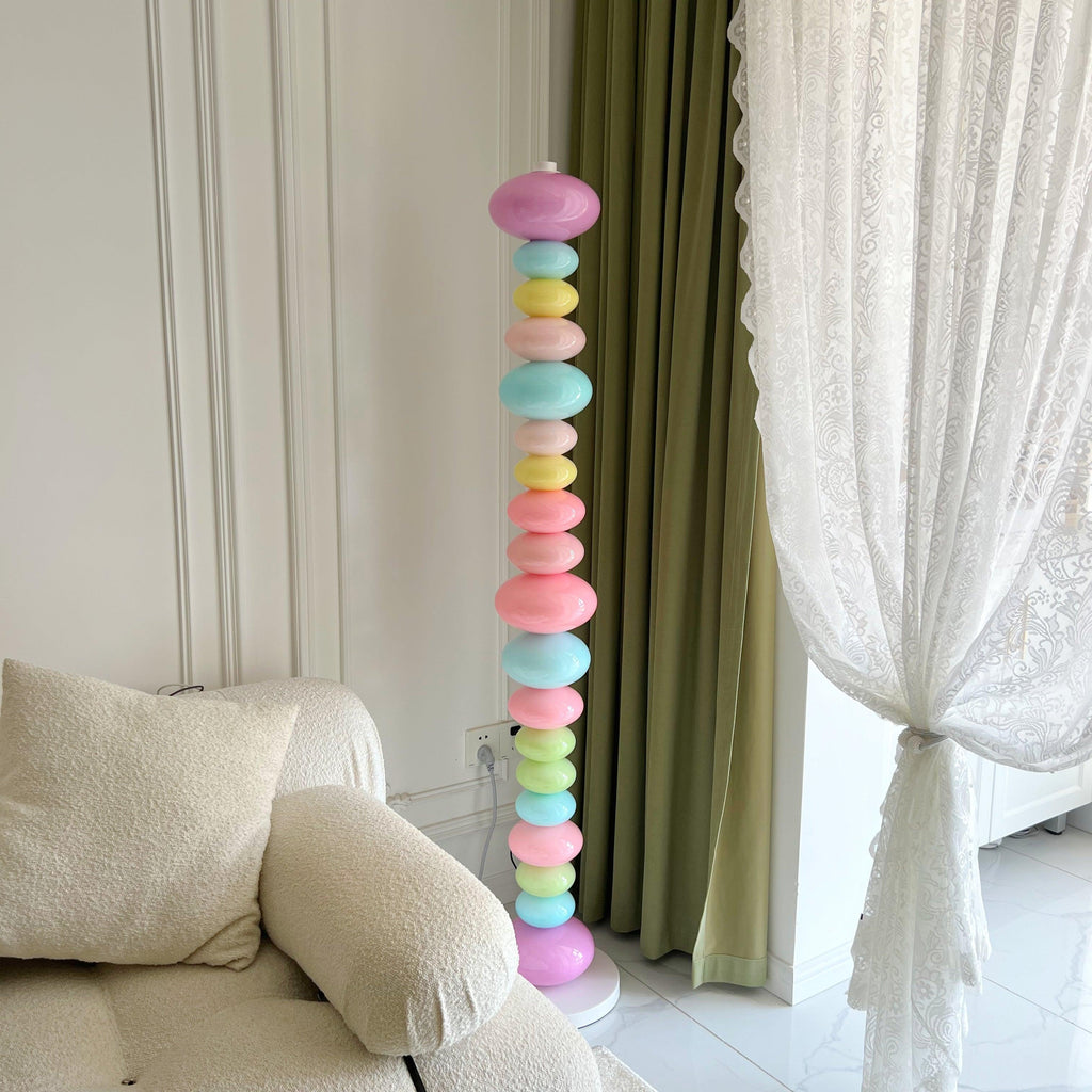 Clérachic pastel floor lamp glowing beside a cream sofa, cropped close against sheer curtains in soft daylight.