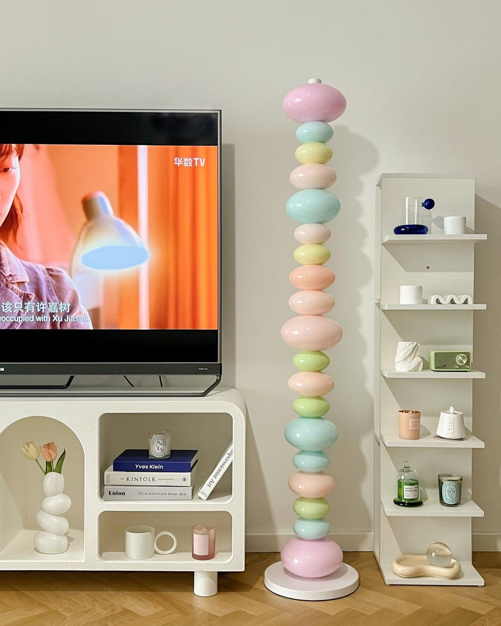 Clérachic glass globe floor lamp glowing beside a media console stacked with books and a small houseplant.