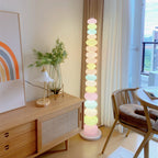 Clérachic pastel glass globe lamp lit beside a rattan-backed chair and wooden sideboard in a sunlit living room.