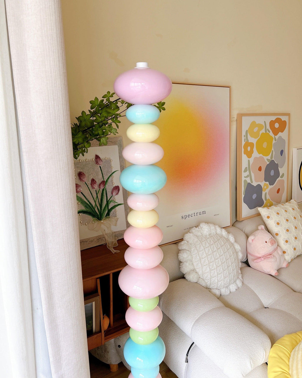 Close crop of a Clérachic glass globe floor lamp lit in a corner styled with floral wall art and a round sun print.