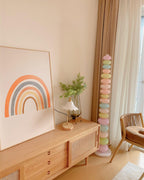 Clérachic stacked glass globe lamp lit beside a wooden console and rattan chair, cropped tighter on the rainbow print.
