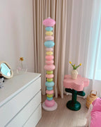 Clérachic pastel floor lamp glowing beside a white dresser, a round mirror and pink bedding just visible behind.