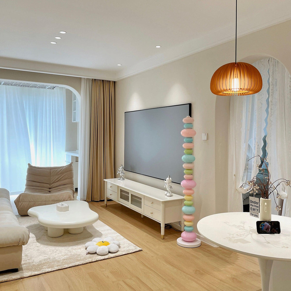 In an open-plan living room, this Clérachic floor lamp's pastel glass globes glow beside a round white coffee table and TV stand.