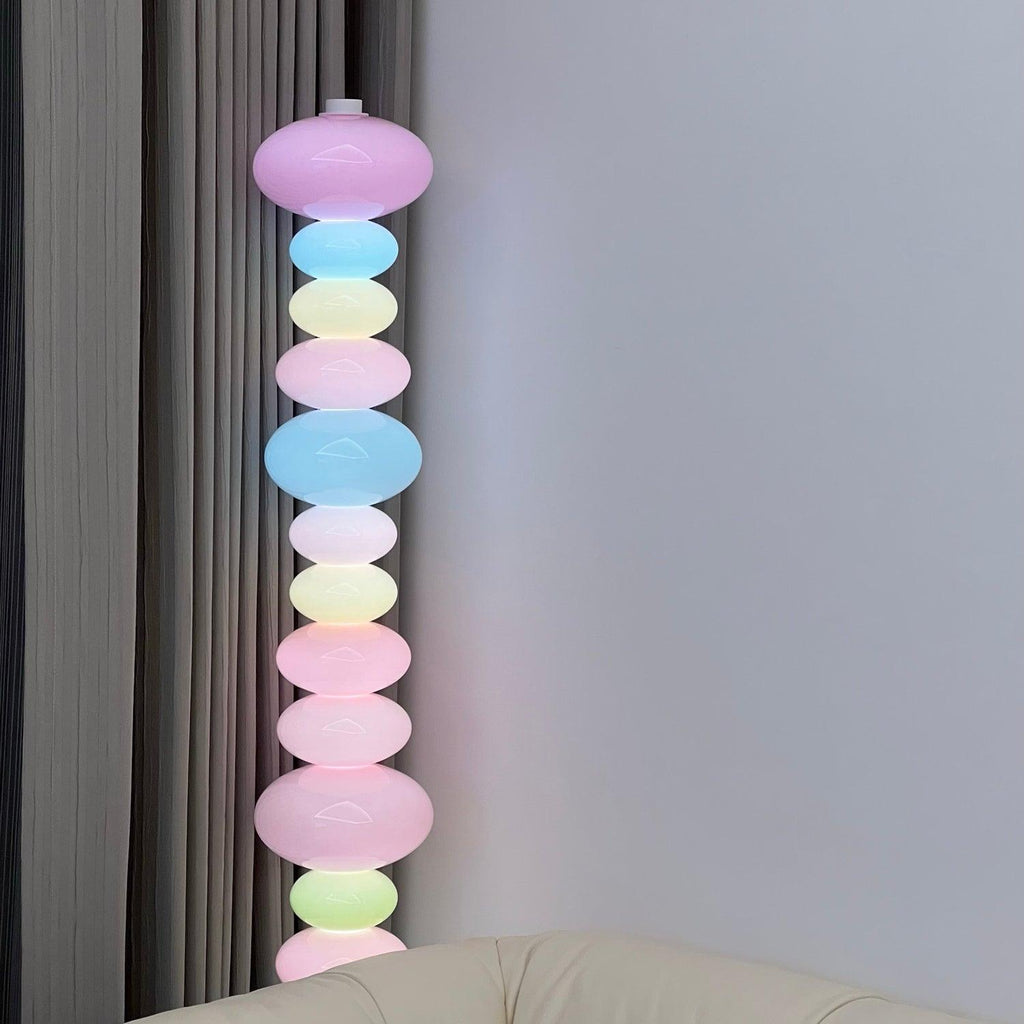 Photographed close against a plain wall, this Clérachic floor lamp shows its full stack of lit pastel glass globes from base to top.