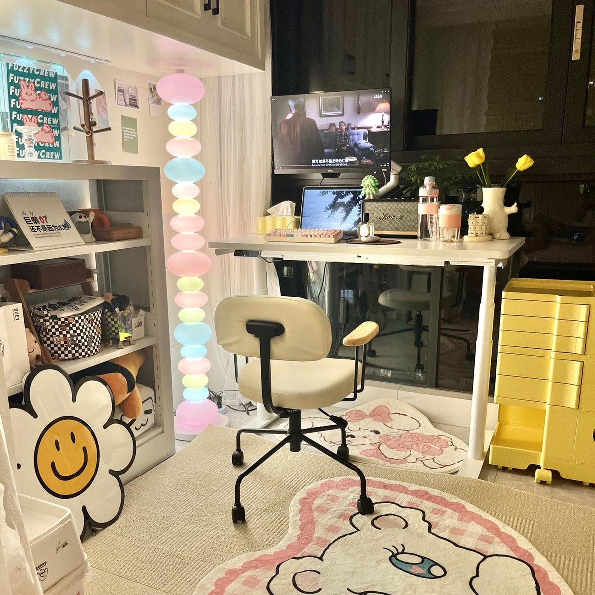 In a home office with a desk chair and floral rug, this Clérachic floor lamp's stacked globes glow beside open shelving.