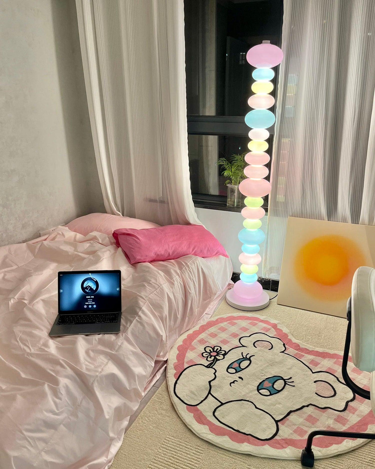 Set beside a bed with a laptop and patterned rug, this Clérachic floor lamp's pastel globes cast a soft glow in the bedroom.