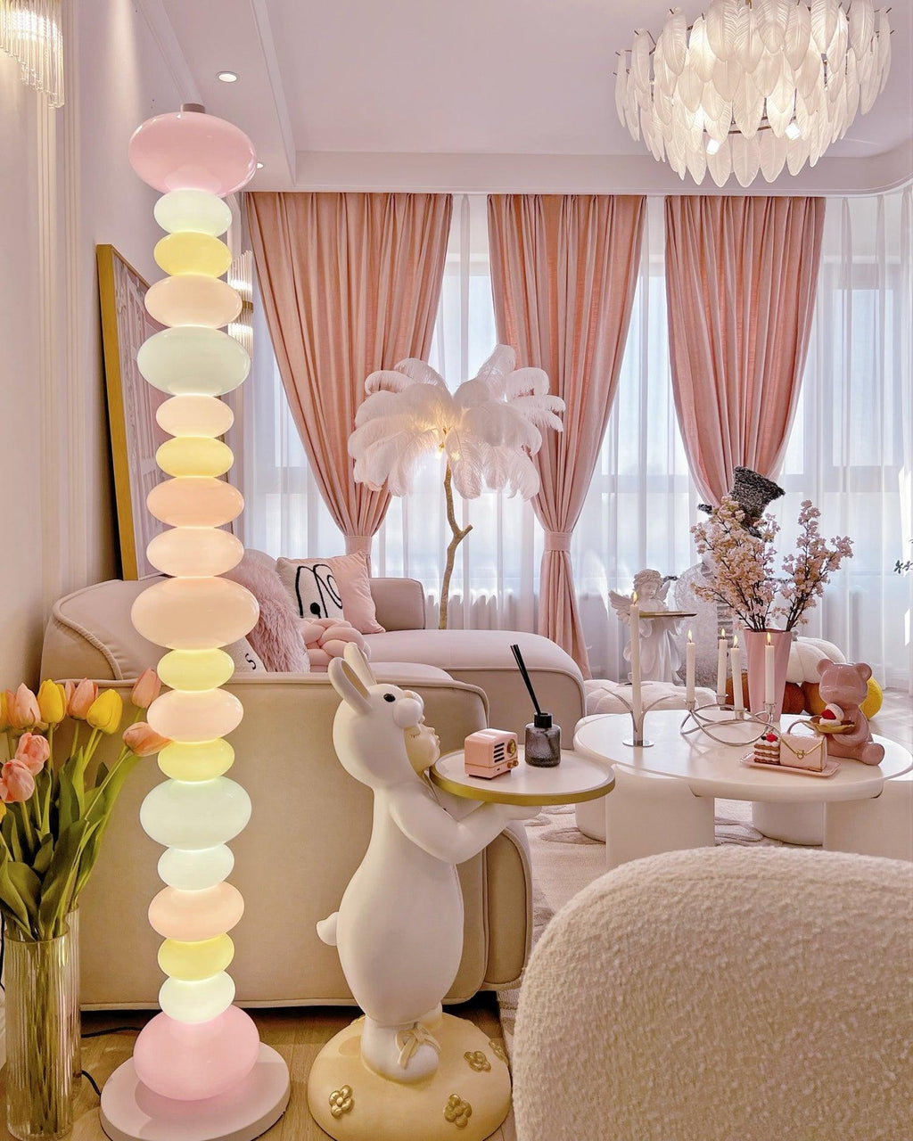 In a pink-toned room with a rabbit figurine and sheer drapery, this Clérachic floor lamp's globes glow beneath a chandelier.