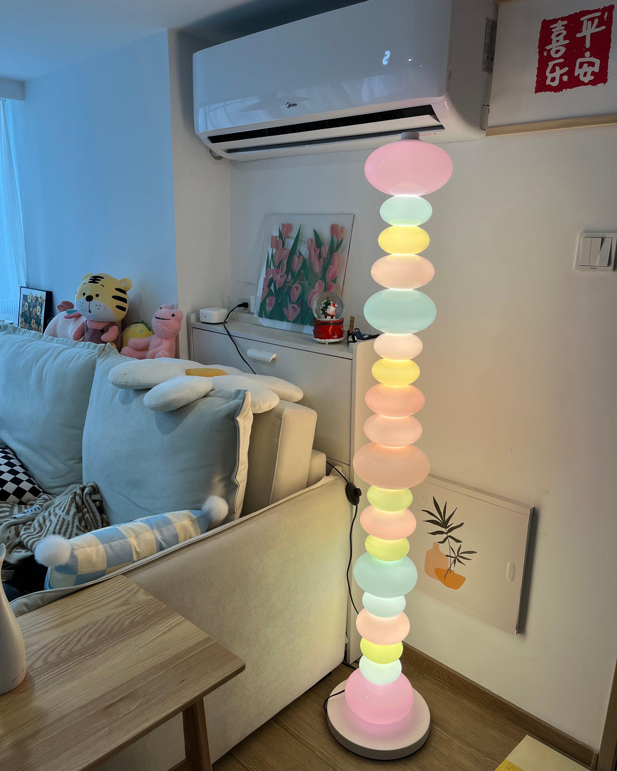 In a bedroom with a plush toy on the bed and wall art nearby, this Clérachic floor lamp's globe column glows warmly.