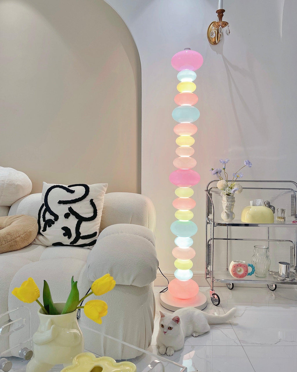 Clérachic glass globe lamp glowing beside a cream sofa and a glass bar cart topped with small bottles and vases.