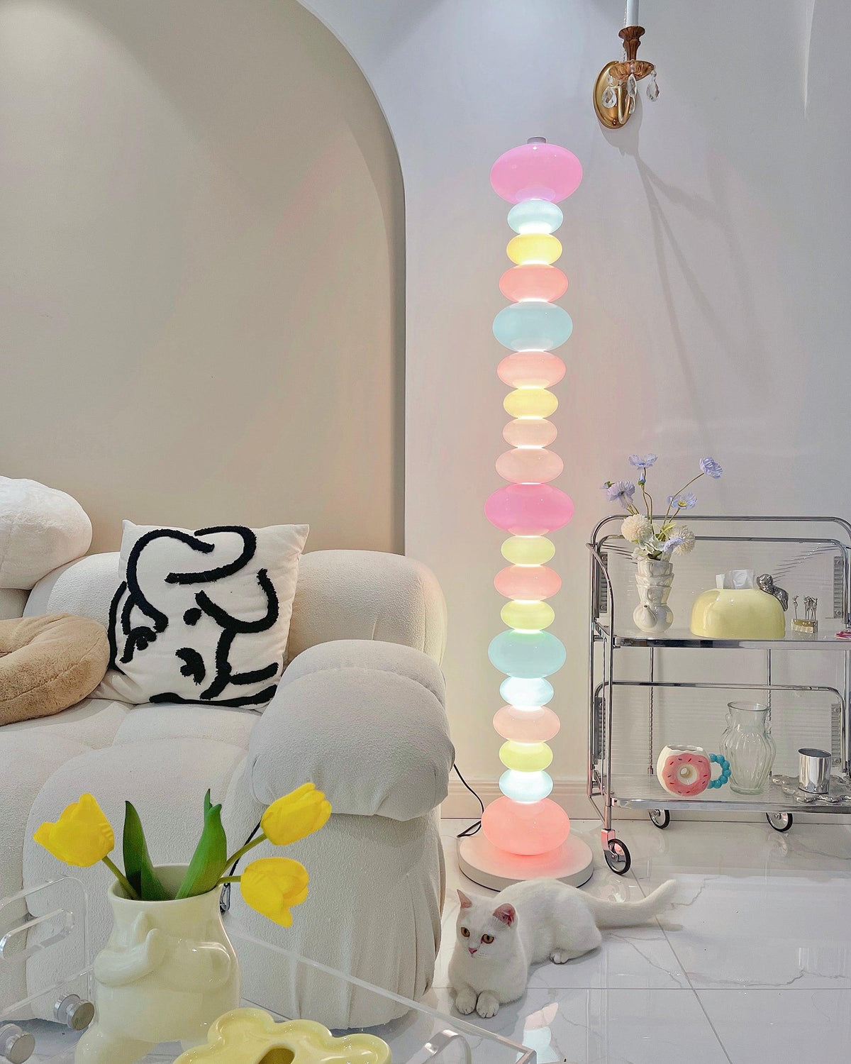 Clérachic glass globe lamp glowing beside a cream sofa and a glass bar cart topped with small bottles and vases.