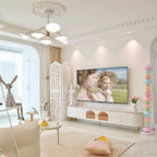 Clérachic stacked glass globe lamp glowing near a white TV console, a vase of tulips and a folding screen.
