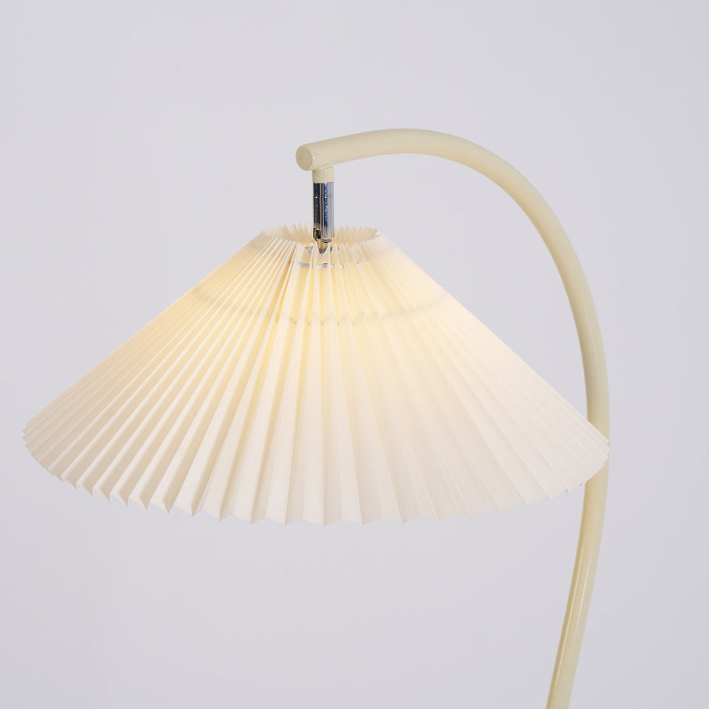 Pleated linen floor lamp glowing warmly beside a chair