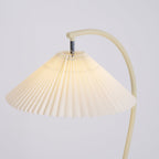 Pleated linen floor lamp glowing warmly beside a chair