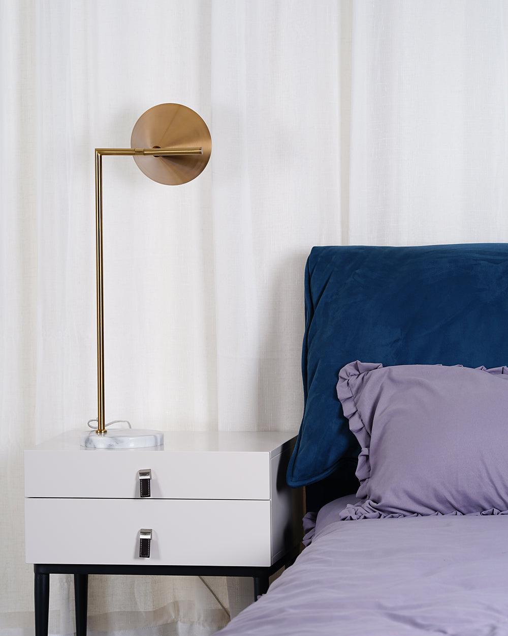 In this frame, a Clérachic brass arm lamp mounts to the wall on a round plate, angling its cone shade over a bedside table.