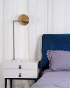 In this frame, a Clérachic brass arm lamp mounts to the wall on a round plate, angling its cone shade over a bedside table.